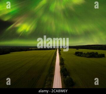 Northern Lights - Aurora borealis over road. Beautiful picture of massive multicoloured green vibrant Aurora Stock Photo