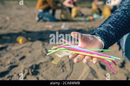 Woman showing handful of straws collected on the beach