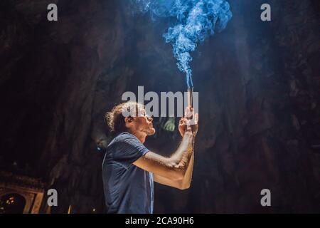 Young man praying in a Buddhist temple holding incense Huyen Khong Cave with shrines, Marble mountains, Vietnam Stock Photo