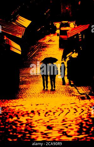 Silhouette of two women under one umbrella walking down a cobblestone alley in Stockholm