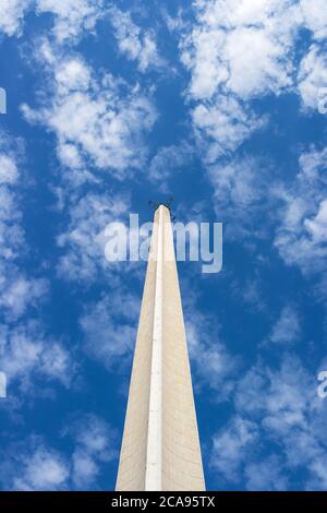 the concrete spire of the antenna rises up against the blue sky and white clouds Stock Photo