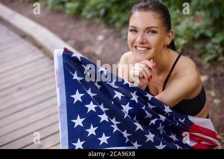 attractive girl posing with american flag in forest park Stock Photo