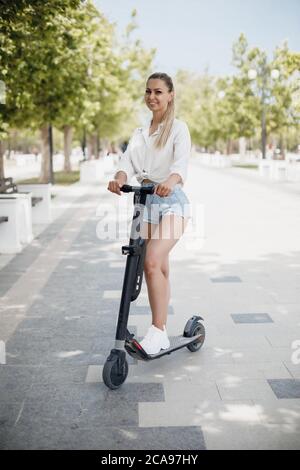 Young woman at electric scooter in the park Stock Photo