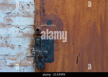 garage door lock with rusty door Combination of screw and padlock Old Orange Padlock on Wooden Blue Gate, Close up Image Stock Photo