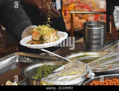 Man serving dabeli at market stall. It is a Gujrati snack made by mixing boiled potatoes with a special spices, putting it in burger bun. Stock Photo