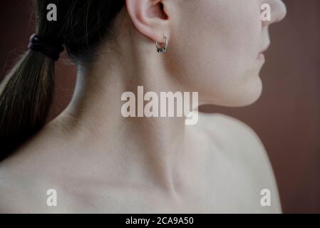 Young Woman neck and chin close up on brown. Selective focus Stock Photo