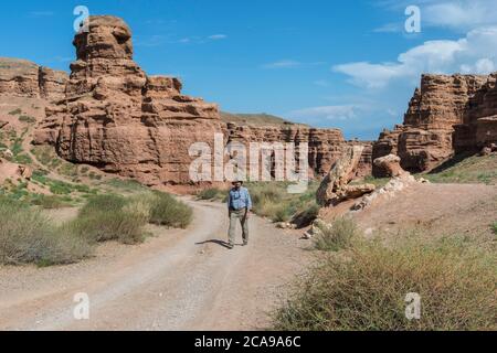 Man walking on the road in Sharyn Canyon National Park and the Valley of Castles, Tien Shan Mountains, Kazakhstan Stock Photo