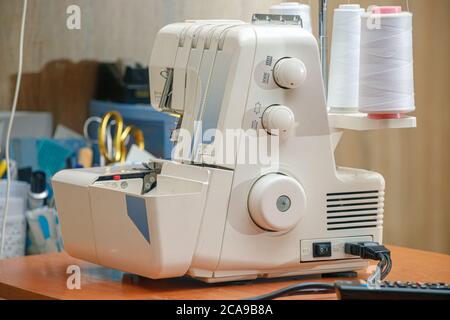 white sewing machine on the table with white threads Stock Photo