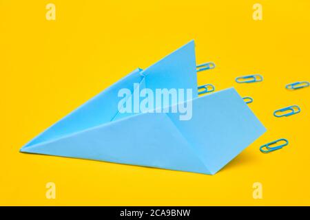 Minimalism, blue paper airplane on yellow background, copy space Stock Photo