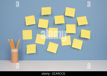Yellow pencils in reusable paper packaging tube with yellow stickers on blue wall background with copy space. Online education or training courses Stock Photo