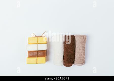 Flat lay composition set for personal hygiene, stack bars of soap and towels on white table. Stock Photo