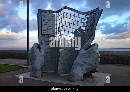 An artwork of two hands holding a gridlike newspaper on Minehead seafront Stock Photo