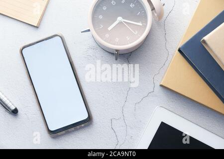 smart phone with empty screen, clock and book on table  Stock Photo
