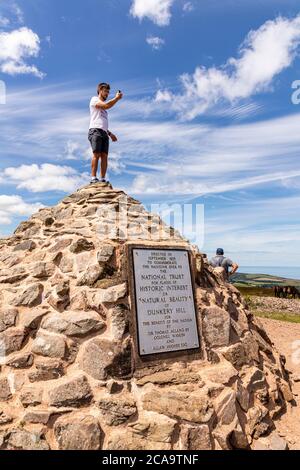 Exmoor National Park - A young man taking a selfie on top of the cairn marking the highest point on Exmoor, Dunkery Beacon, Somerset UK Stock Photo