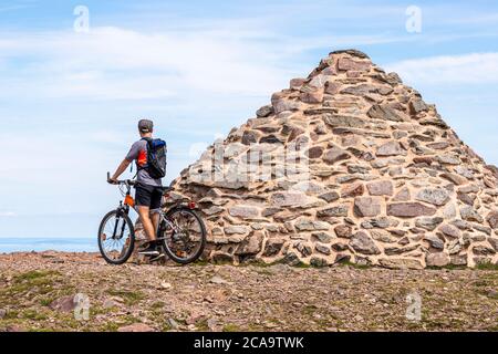 Exmoor National Park - A mountain biker enjoying the view from the cairn marking the highest point on Exmoor, Dunkery Beacon 1705 feet 520 metres, Som Stock Photo