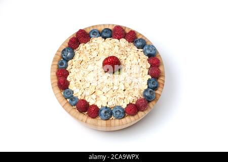 Breakfast cereal with blueberry, raspberry and strawberry in wooden bowl over white background. Top view. Stock Photo