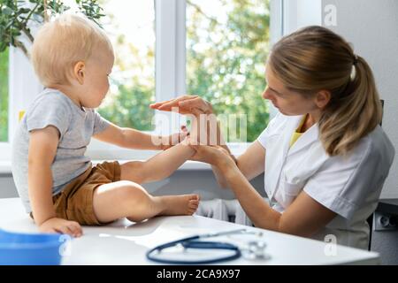 female orthopedist examining little child foot condition in clinic Stock Photo