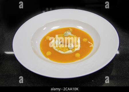High cuisine dessert: Mango Ice cream  with jelly mango fruit in a white meringue, on a black background. 45 degree view angle on a isolated plate Stock Photo