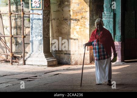 Mayiladuthurai, Tamil Nadu, India - February 2020: An elderly Indian woman walking in a dark hall inside the ancient Hindu temple of Vaitheeswaran Koi Stock Photo