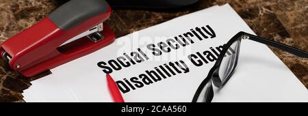 Social Security Disability Claim Concept. An application form on the table next to a red pen and glasses Stock Photo