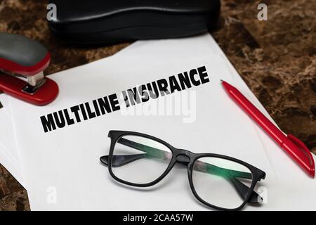 Multiline insurance, an effective insurance tool. Text on white paper, next to black glasses, red pen and hole punch. Stock Photo