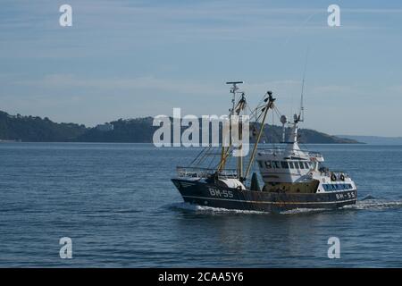 Brixham Trawler BM55 Angel Emiel returning to Brixham harbour Close up side view Headland in distanced Calm sea light blue sky Landscape format Stock Photo