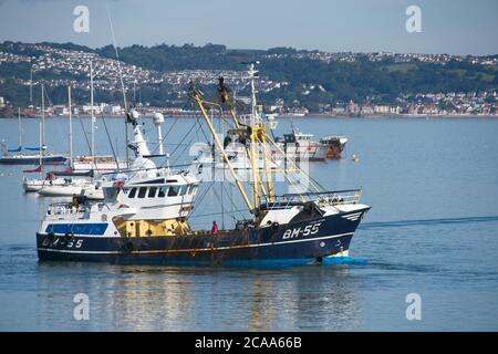 Brixham Trawler BM55 ANGEL EMIEL returning to port. Large seagoing trawlers moving around in Brixham harbour Side view Calm sea Light blue sky Stock Photo