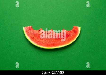 Single slice of watermelon top view on a green table. Eaten watermelon isolated on a colored background. Very juicy and refreshing summer fruit. Stock Photo