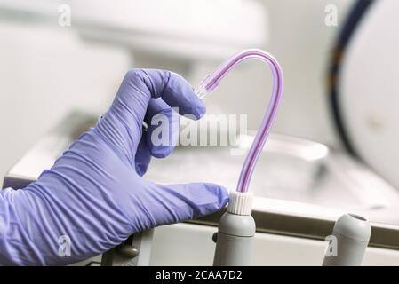 Hand in Blue latex glove and saliva ejector symbolize love in dentistry. Heart symbol. Dental treatment, healthcare and dentistry concept. Stock Photo