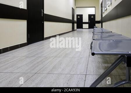 empty corridor in the modern office building. There are many brown doors along a very long corridor with beige walls. Stock Photo