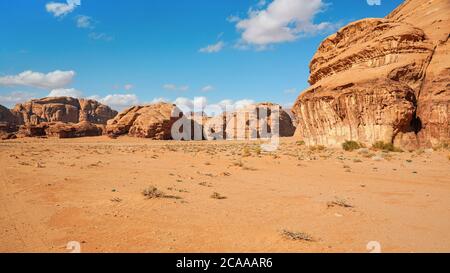 Rocky massifs on red sand desert, bright blue sky in background - typical scenery in Wadi Rum, Jordan Stock Photo