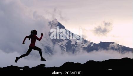 Running woman athlete trail running in mountain summit background. Female runner on run training outdoors living active fit lifestyle. Silhouette at Stock Photo