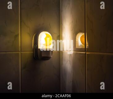 A night light with a sensor detecting movement switched on inside a dark bathroom Stock Photo