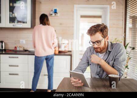 Portrait of pleasant intelligent caucasian businessman reading news on smartphone, drinking coffee and talking to casually dressed woman. Stock Photo