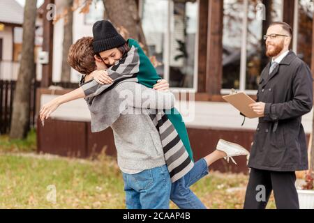 Family, people, real estate purchase of a real property concept - smiling couple standing outdoor in house yard, hugging after signing the property sa Stock Photo