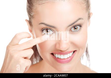 Young woman holding contact lens on index finger looking at you smiling with toothy happy smile. Close up face of healthy beautiful woman about to wea Stock Photo