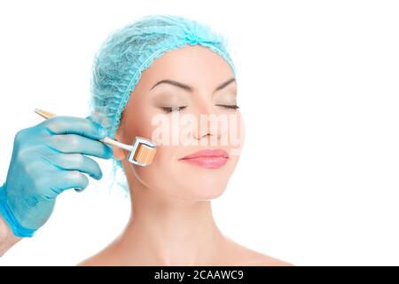 Medical cosmetic procedure. Micro-needling therapy. Beautician performs Dermaroller procedure, young beautiful woman having an injection mesotherapy i Stock Photo