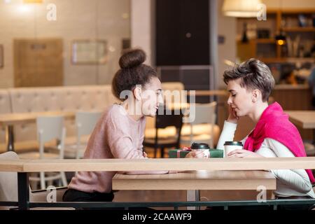 Two young female friends having coffee break together, having fun in shopping centre cafe. Holidays, shopping, relationships concept-Women enjoying co