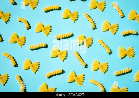 Uncooked curly pasta pattern on blue background. Traditional dry raw macaroni pattern. Nobody Stock Photo