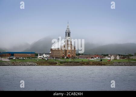 tranquil scene of an Acadian village abroad the sea in Cheticamp with church and small houses in  rural country of Nova Scotia, Canada Stock Photo