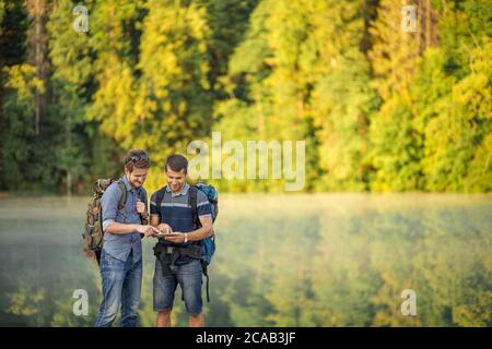 two pleasant tourists are looking at the photos which they have taken on the mountains. copy space. send e-mail. download music Stock Photo