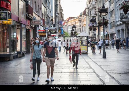 BELGRADE, SERBIA - JULY 21, 2020: Young people, a couple, walking and holding hands in a Belgrade street wearing face mask protective equipement on Co Stock Photo