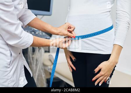 Doctor measuring pregnant girl's belly. close up side view cropped photo.pregnancy concept. woman visiting a gynecologist Stock Photo