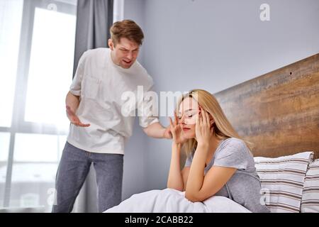 how much one can sit offended,do the housework dissatisfied man want her lazy wife to do housework, offended woman sits on bed Stock Photo