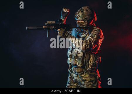 powerful and strong military man in military forces wear and helmet pointing rifle at enemy, ready to shoot, fight for country, isolated in ultra viol Stock Photo