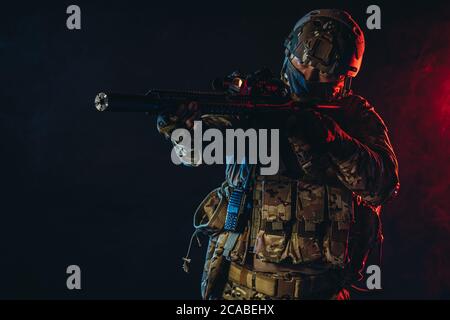 powerful and strong military man in military forces wear and helmet pointing rifle at enemy, ready to shoot, fight for country, isolated in ultra viol Stock Photo