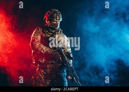 courageous soldier man in green military wear holding gun, rifle in hands, don't afraid of danger, looking for enemy Stock Photo