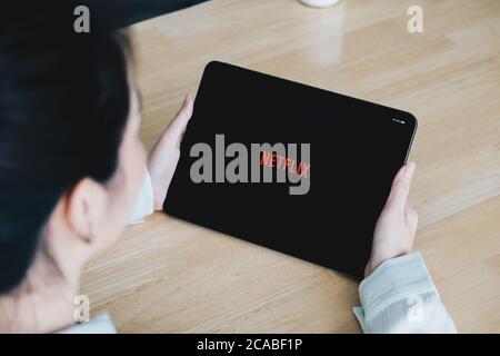 CHIANG MAI, THAILAND, JULY 26, 2020: Woman hand holding Smart tablet with Netflix logo on Apple iPad. Netflix is a global provider of streaming movies Stock Photo