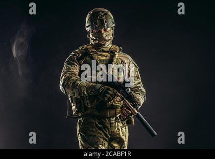 brave strong and confident man soldier wearing army clothes, green camouflage stand holding gun, ready to shoot Stock Photo