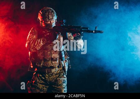 powerful and strong military man in military forces wear and helmet pointing rifle at enemy, ready to shoot, fight for country, isolated in ultra viol Stock Photo